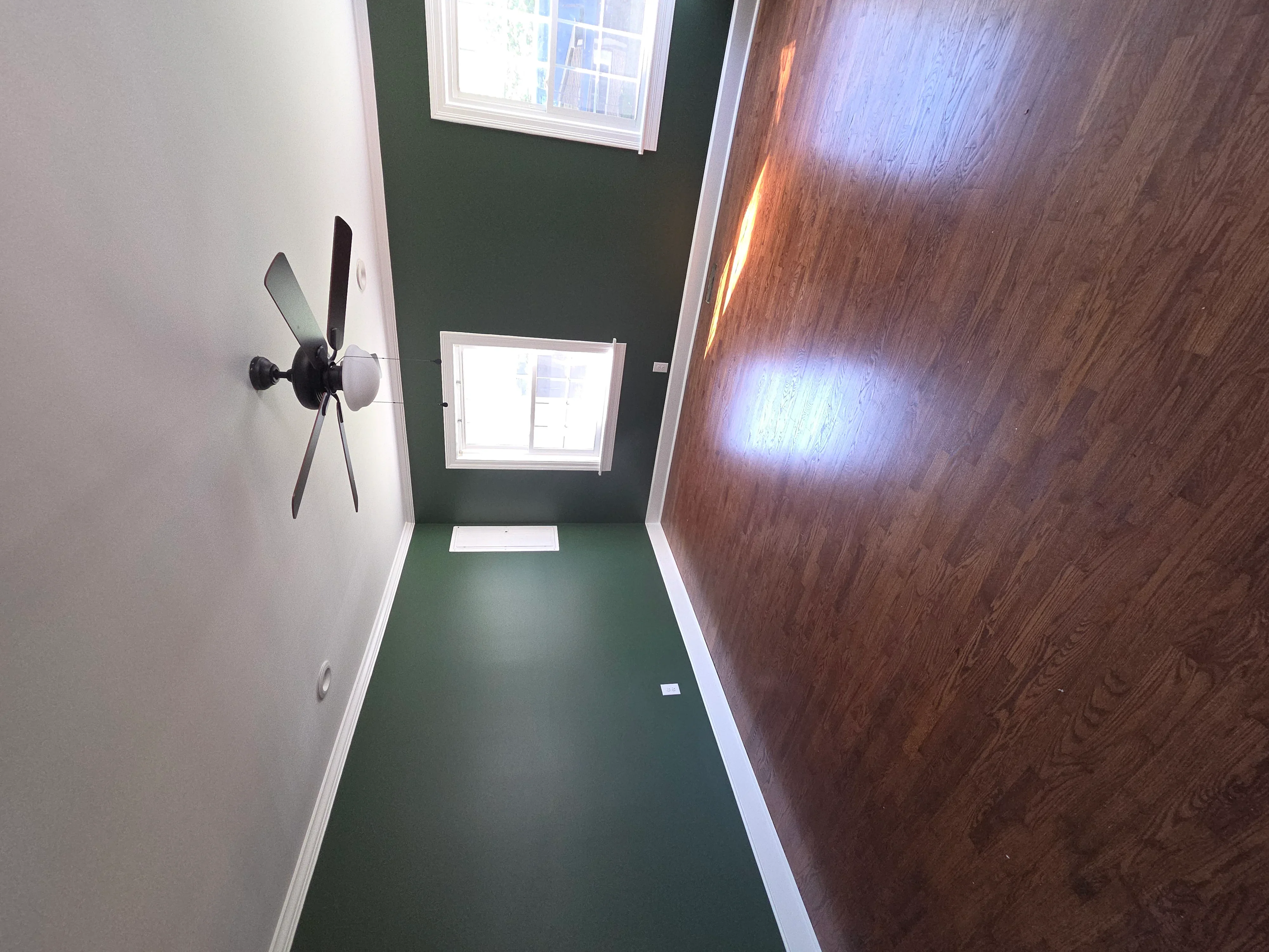 Hallway with forest green walls, white trim, wood flooring, and recessed lighting