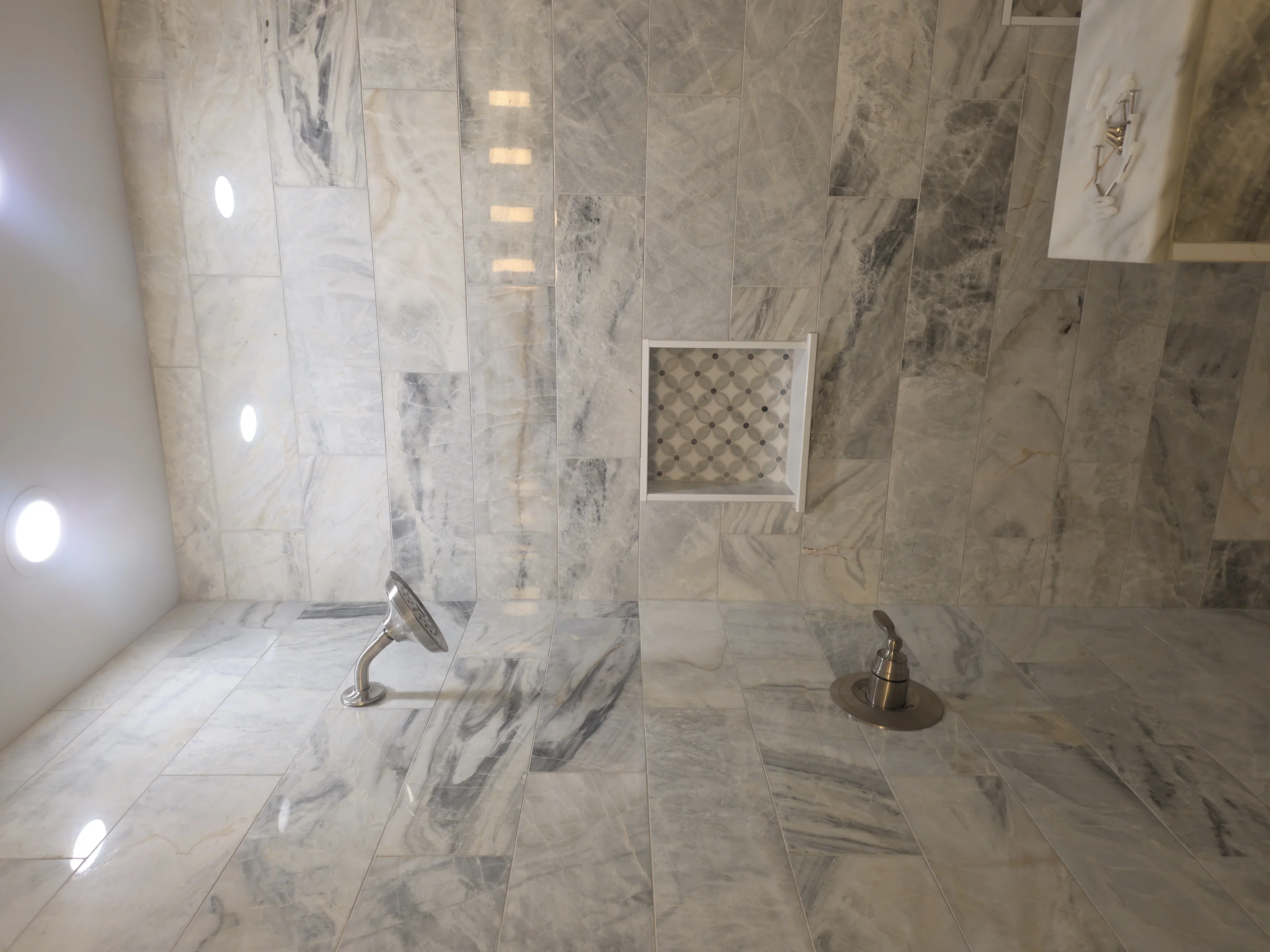 Marble tile shower with dual showerheads and built-in niche
