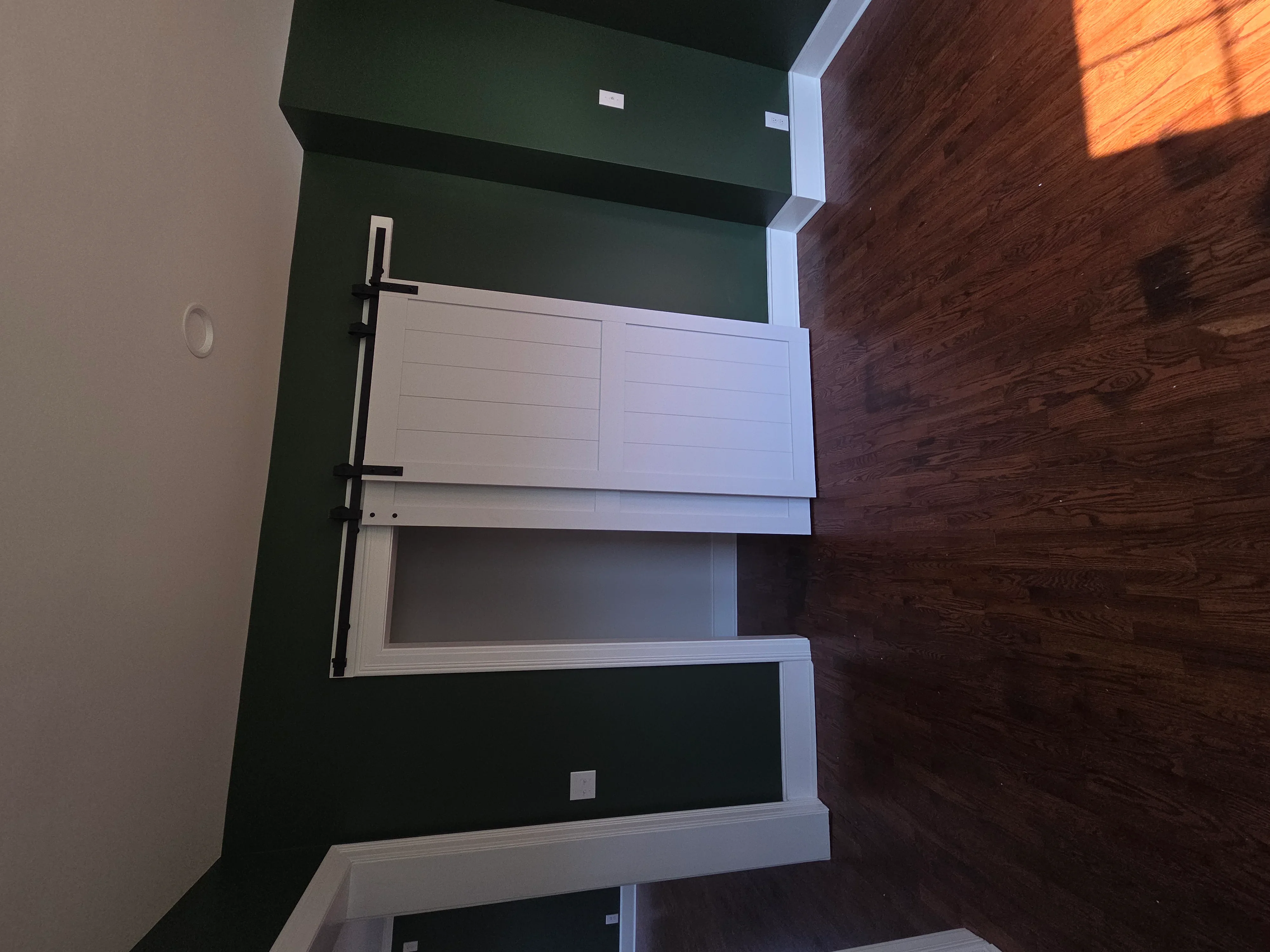 Modern bathroom vanity with white cabinetry and black hardware against forest green walls
