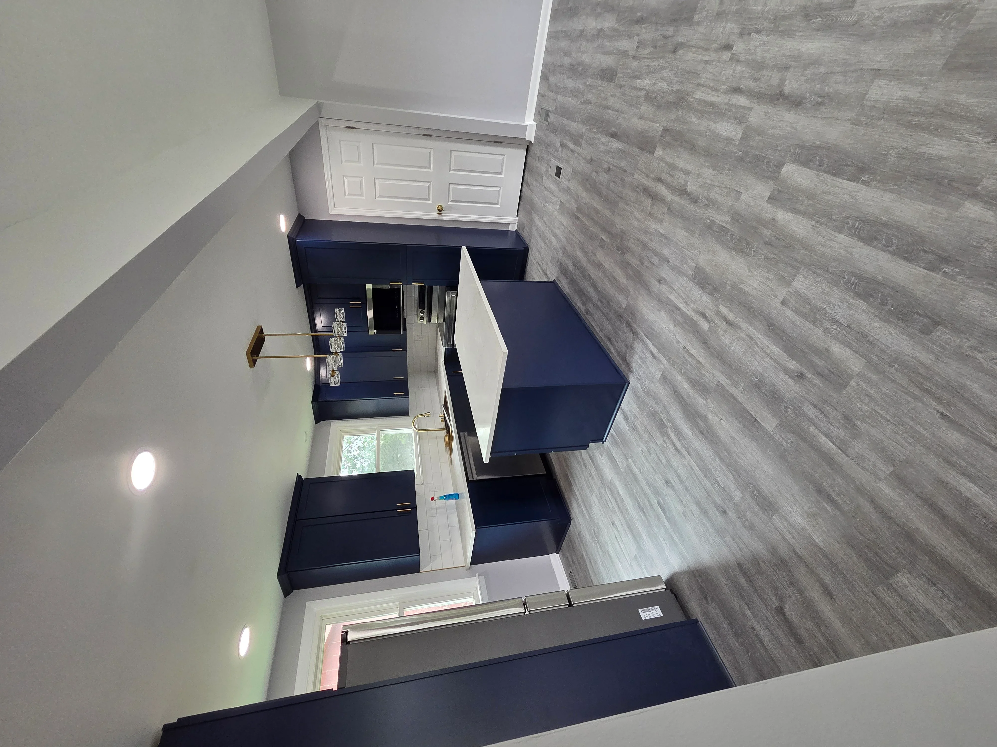 Bathroom remodel with gray wood flooring, navy cabinetry, and white painted walls