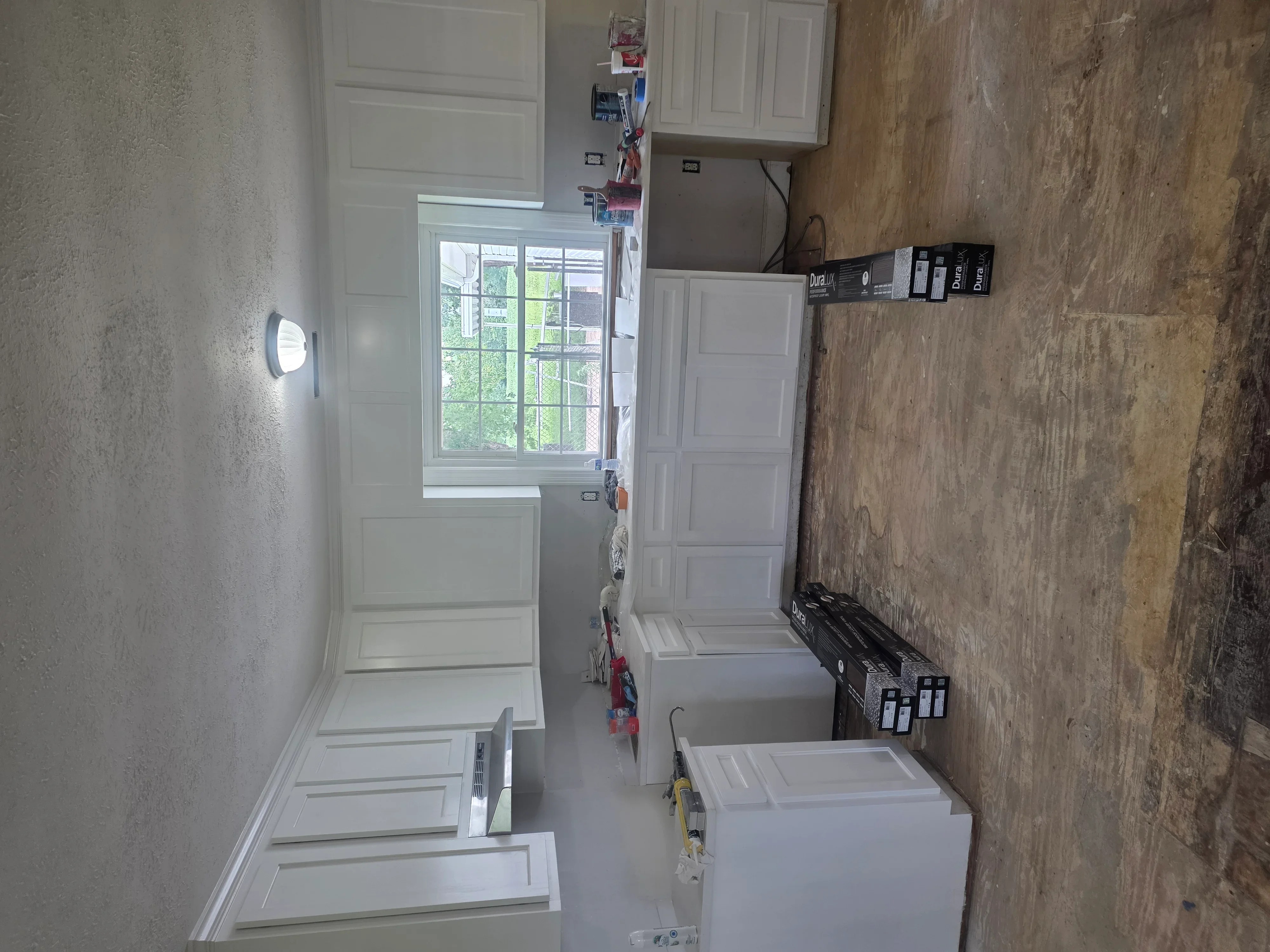 Kitchen remodel in progress with white cabinets and wood-look tile flooring