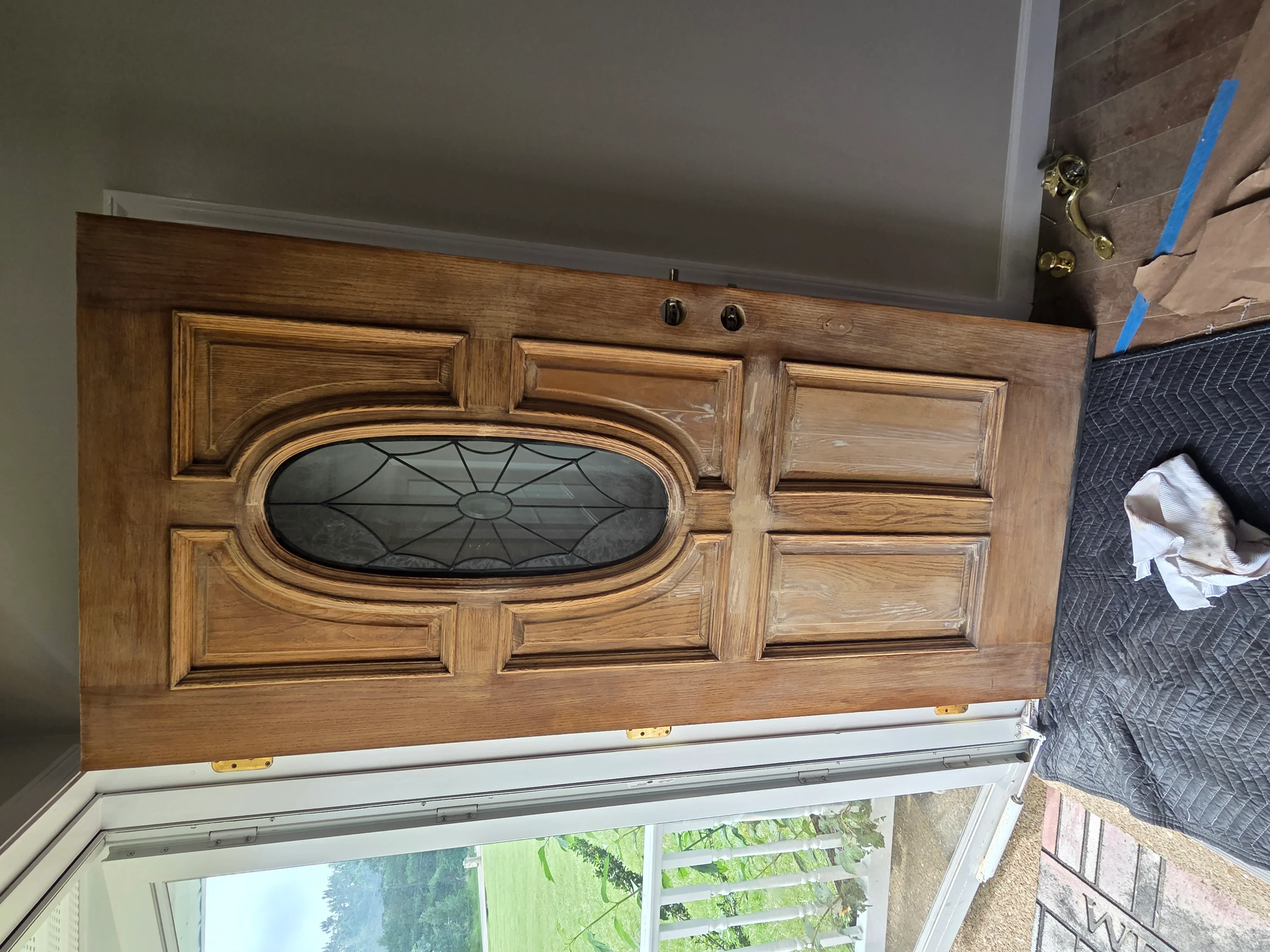 Custom oak transom door with oval leaded glass insert above sliding glass doors