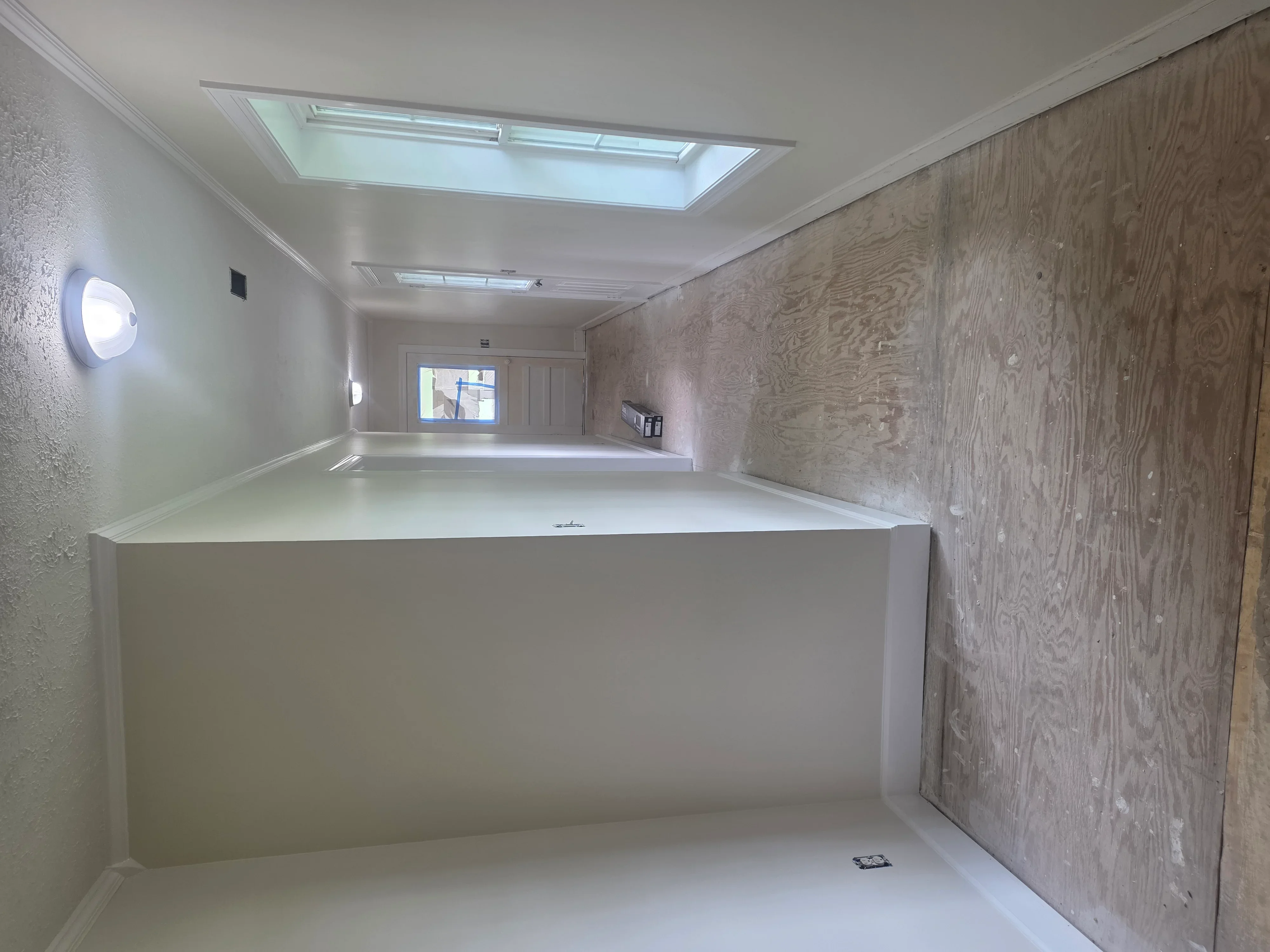 Commercial interior with finished drywall, textured wood-grain accent wall, and skylight ceiling