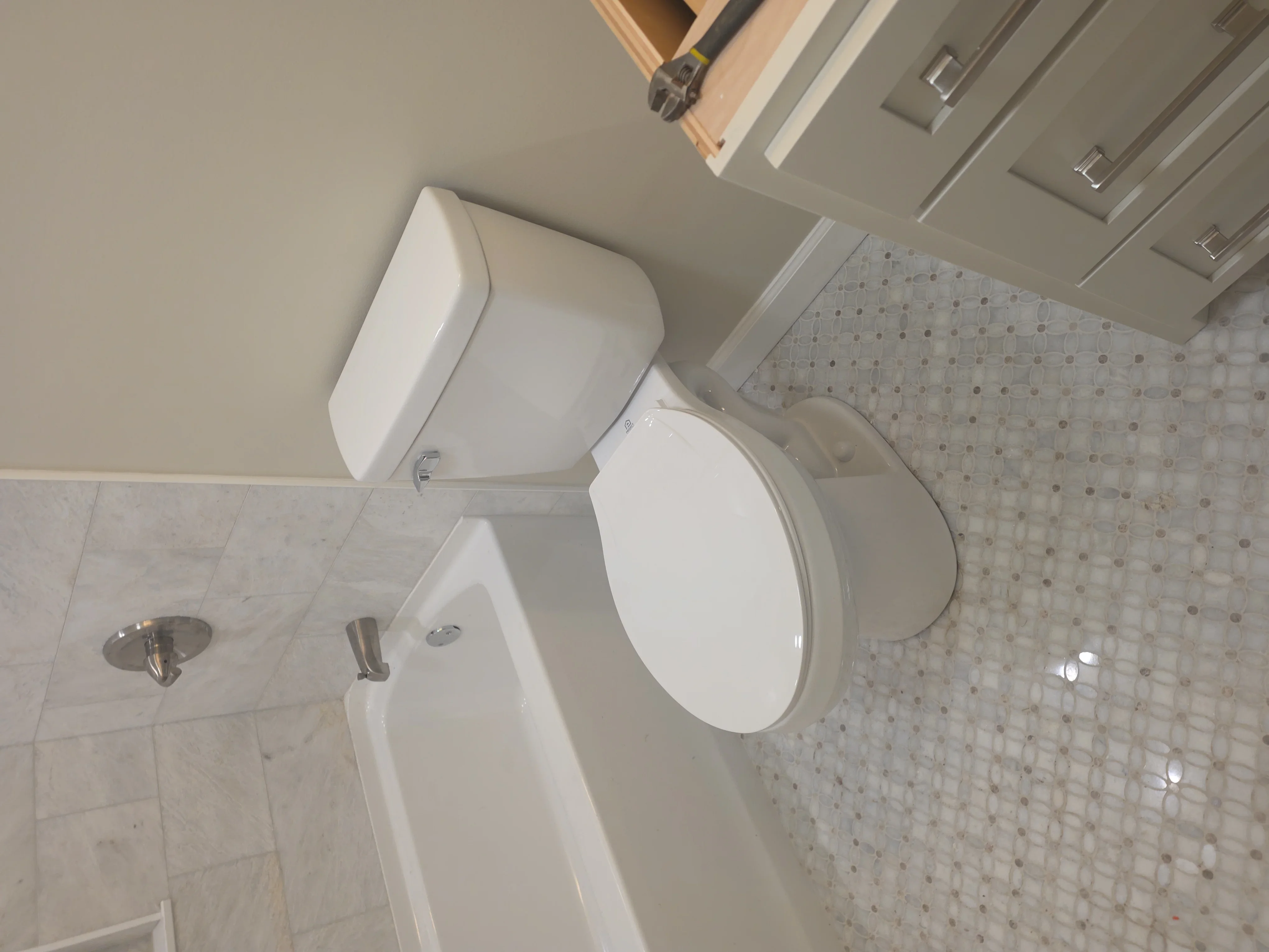 Renovated bathroom with white tile floor, new fixtures, and neutral painted walls