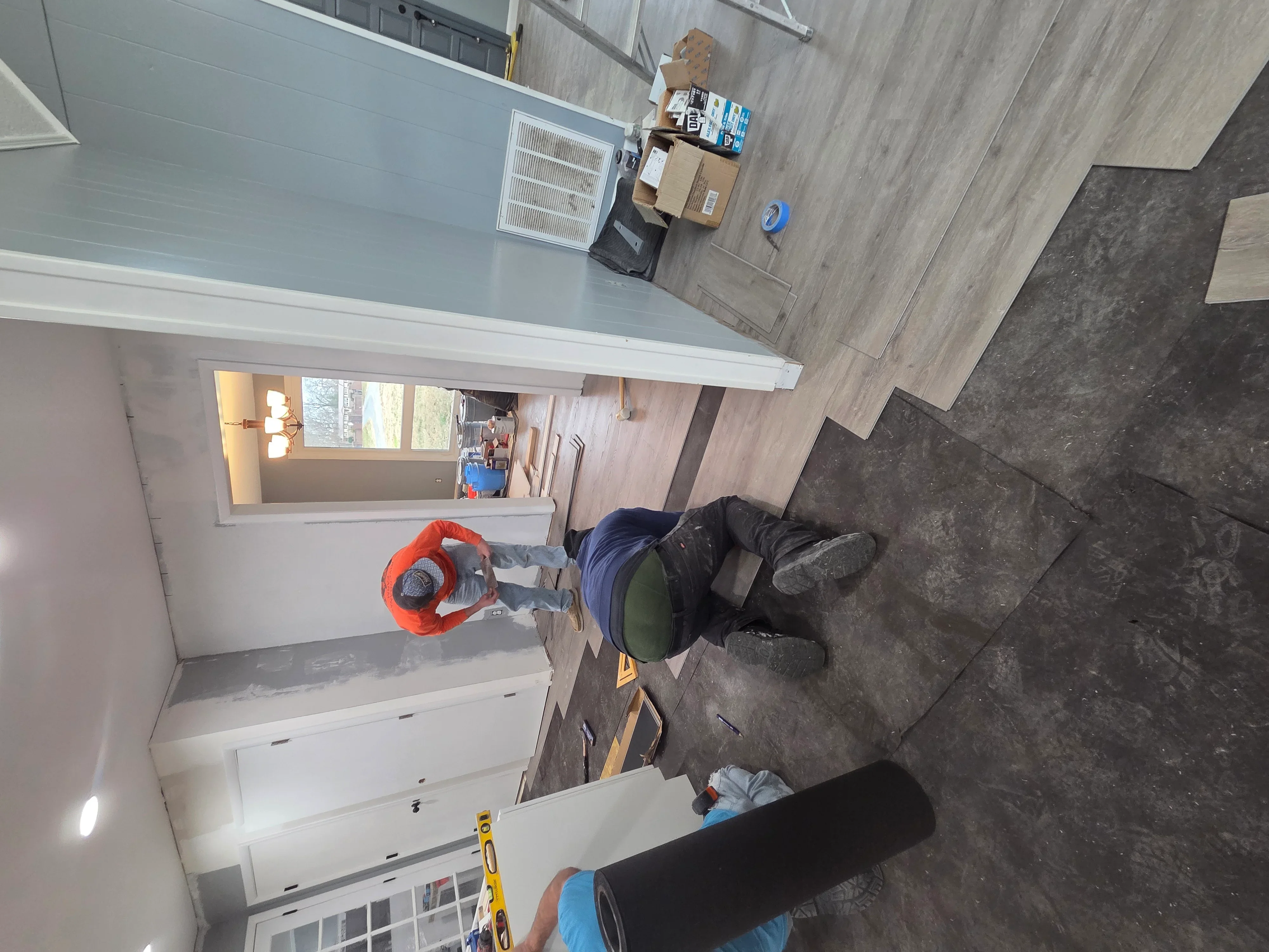 Kitchen remodel in progress showing white cabinetry installation and drywall work