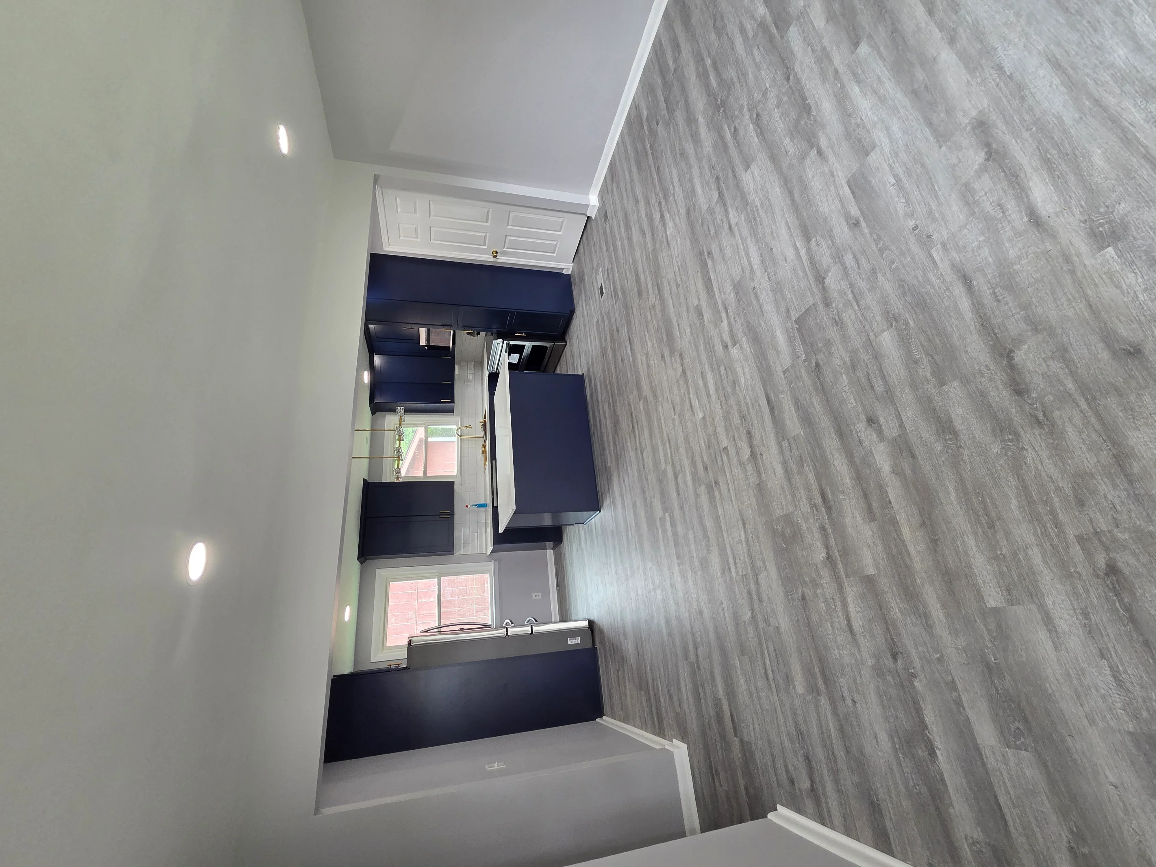 Modern bathroom with gray wood-look tile walls, dark vanity cabinet, and recessed lighting