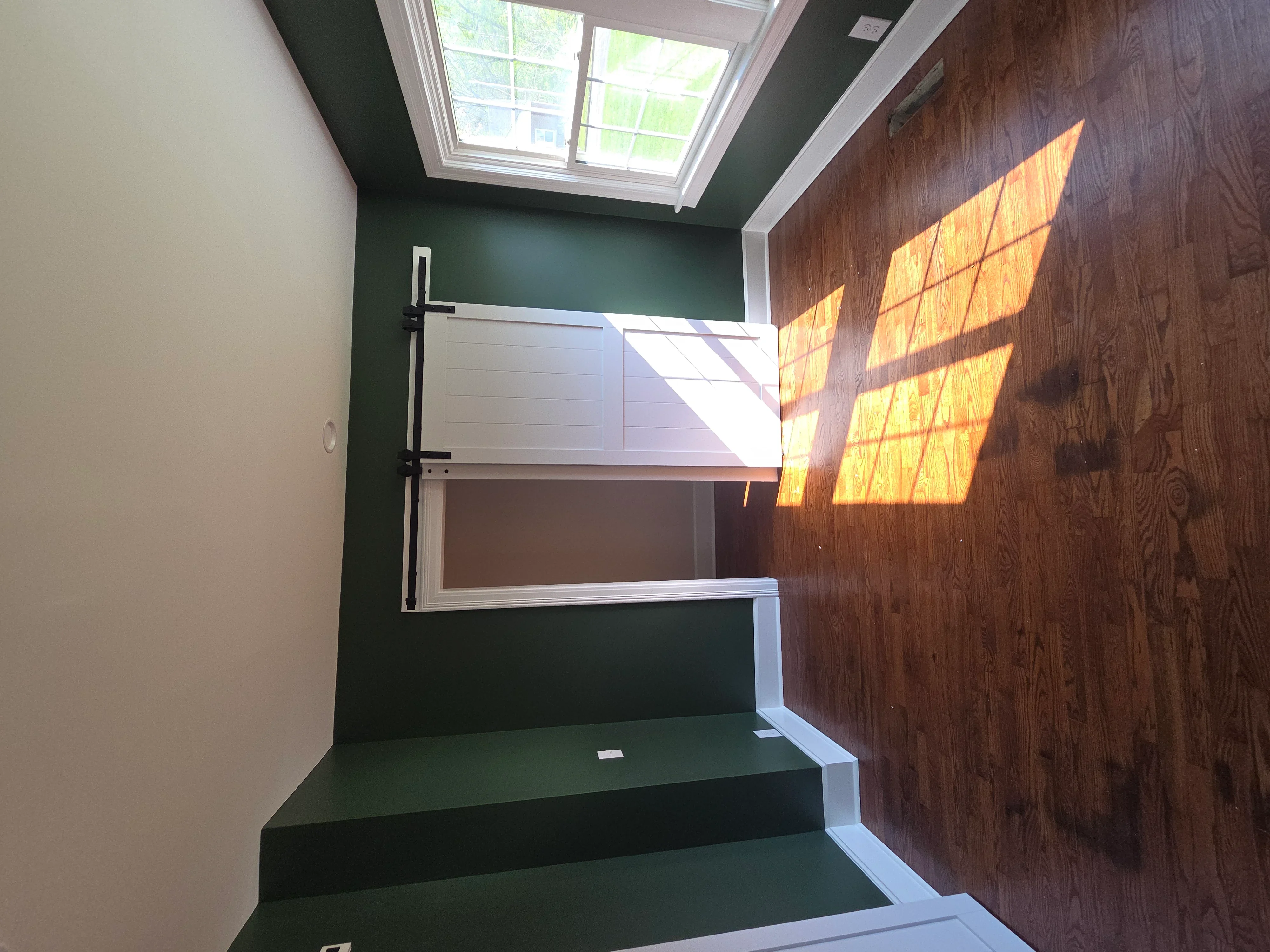 Stairwell with dark green walls, wood flooring, skylight, and white trim
