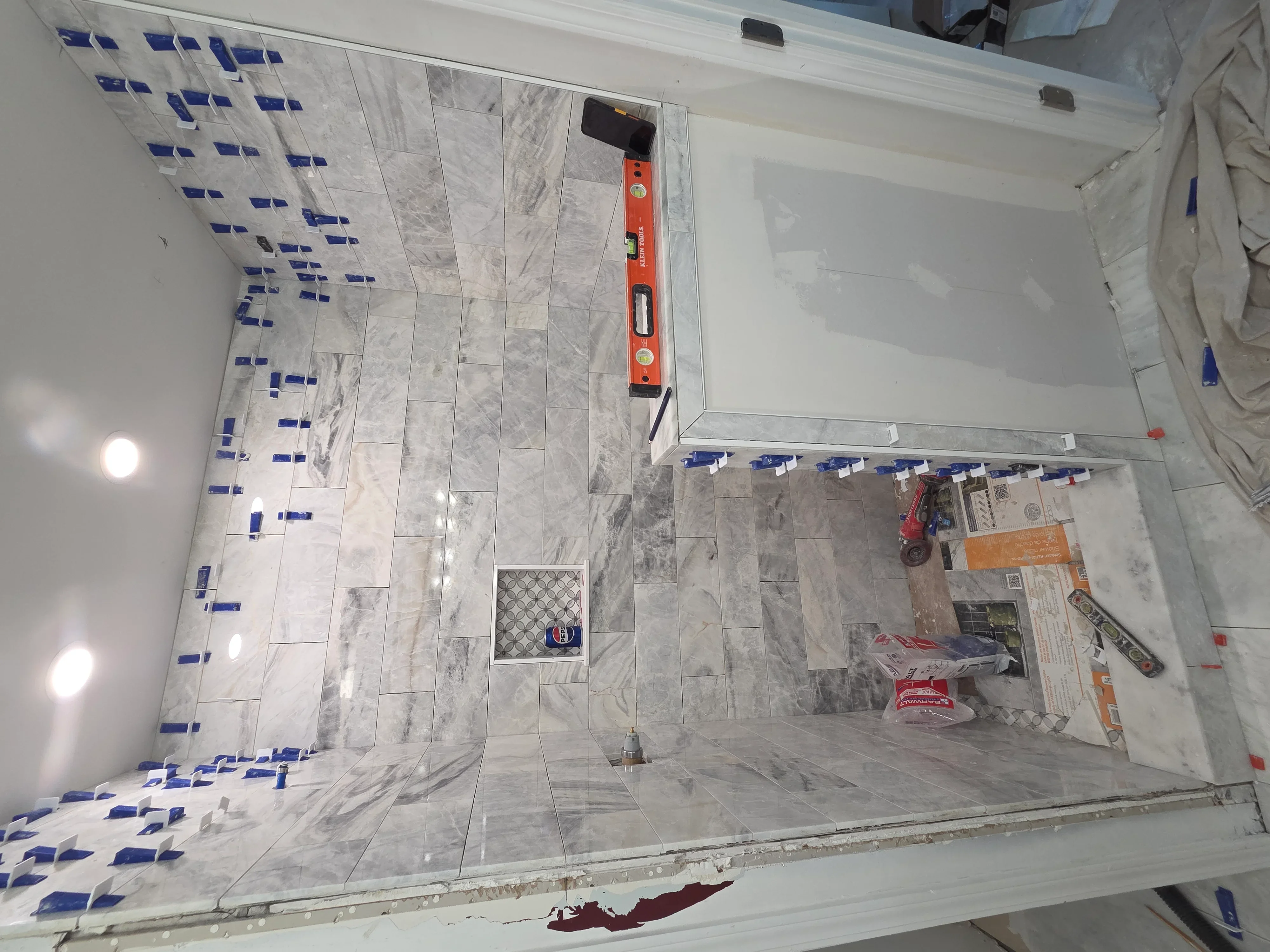 Bathroom tile installation in progress with marble-look porcelain tiles and custom shower niche