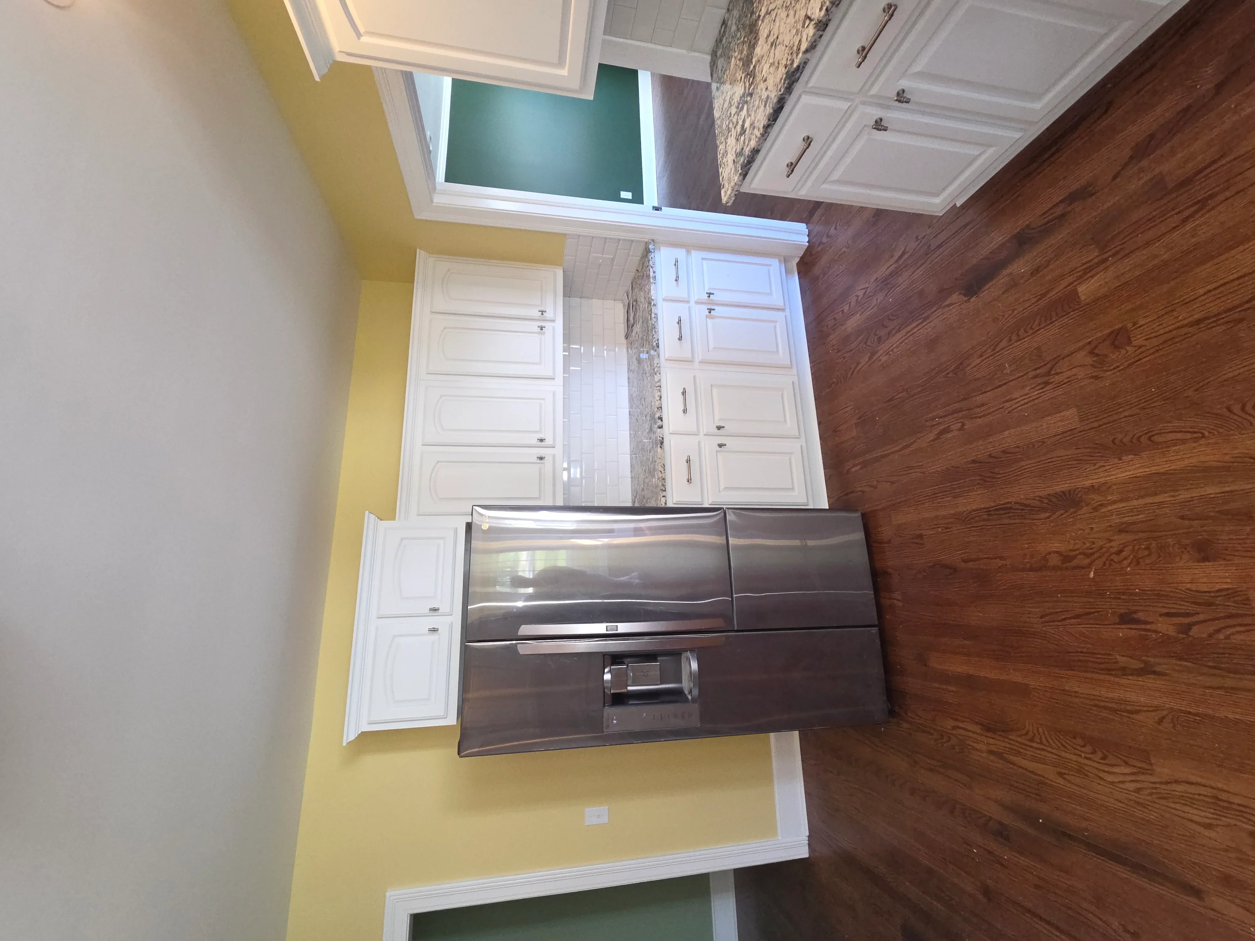 Modern kitchen with white cabinets, wood flooring, and yellow walls