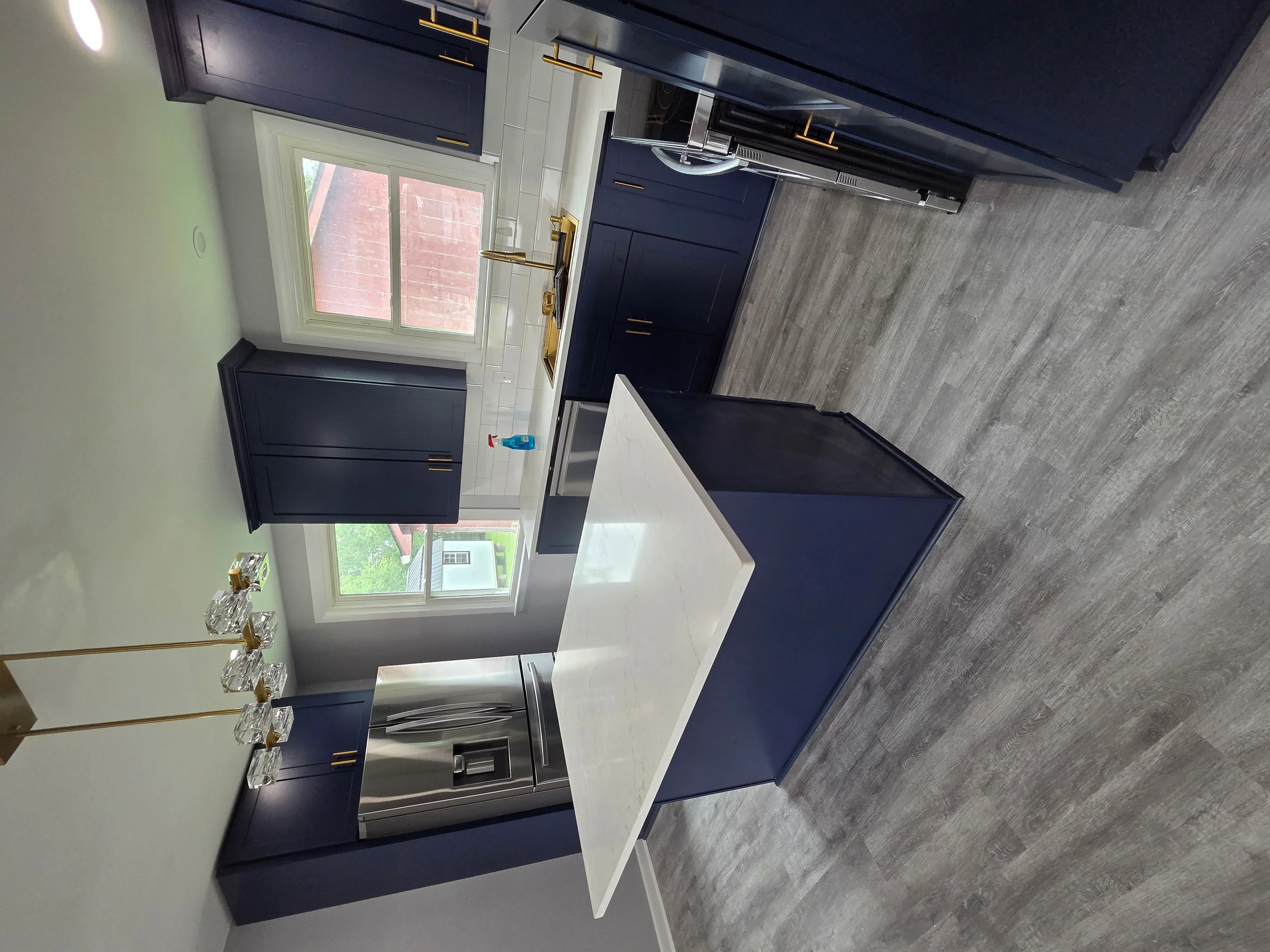 Modern kitchen with navy cabinets, gray flooring, and white subway tile backsplash