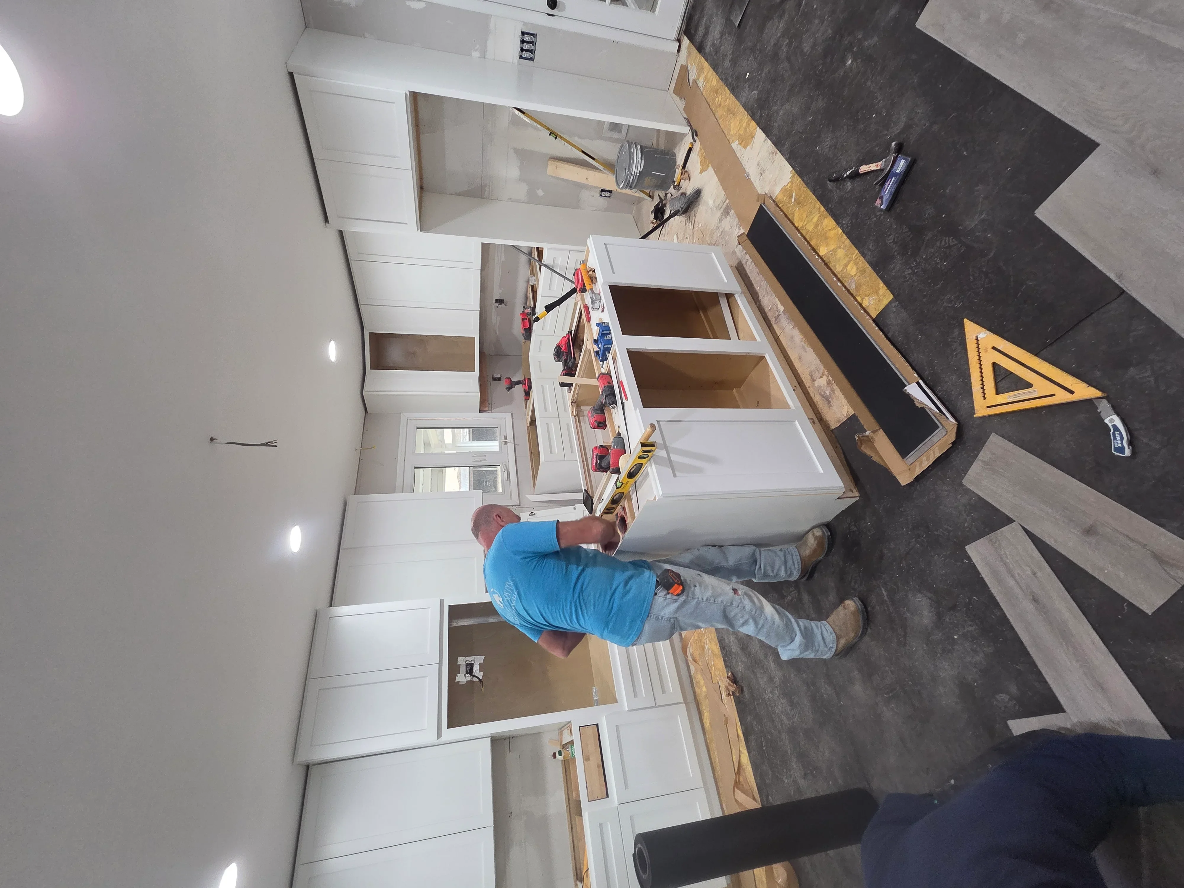 Kitchen remodel in progress with white cabinetry and open shelving installation