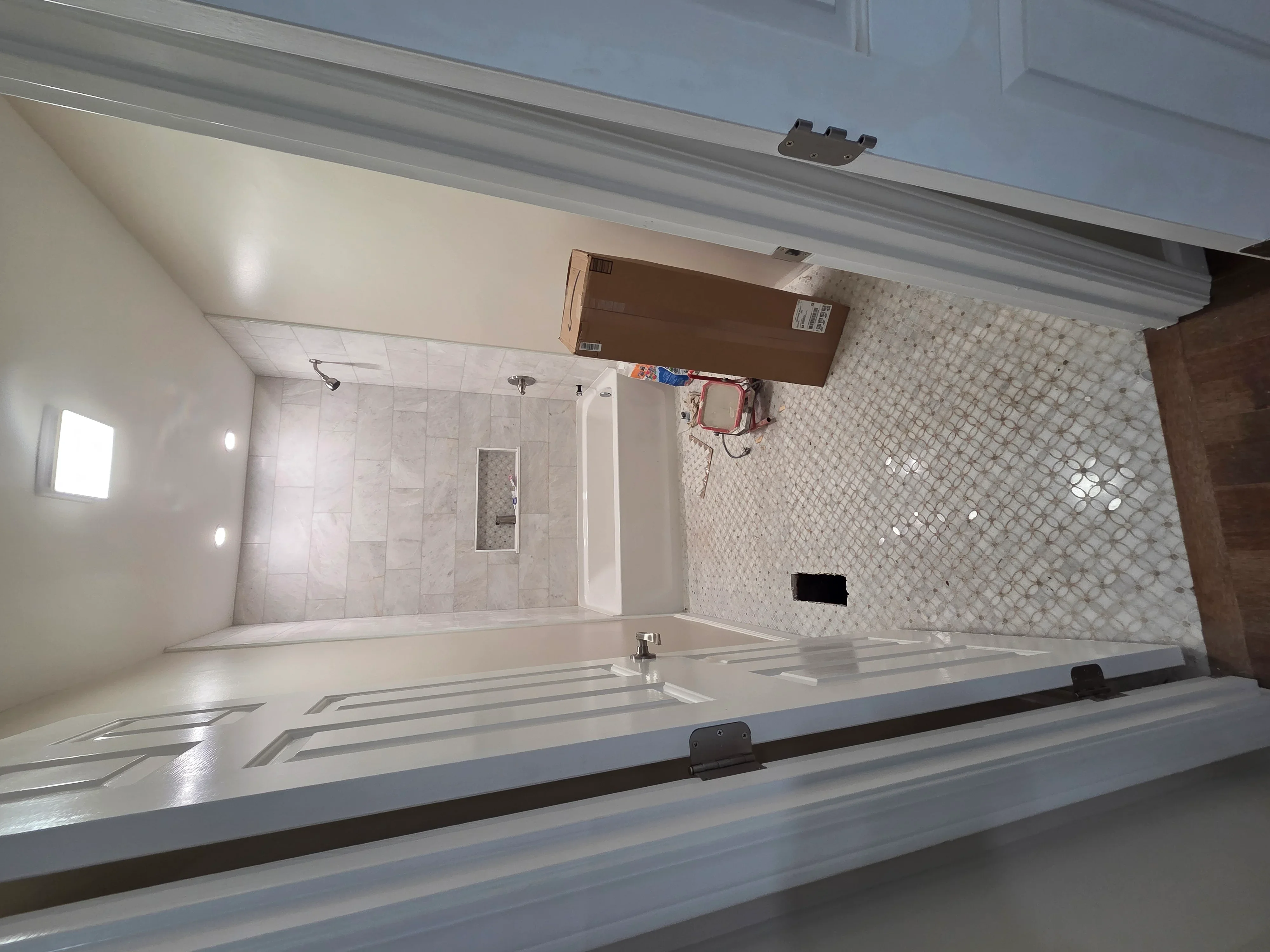 Modern bathroom with marble tile shower, mosaic accent wall, and recessed lighting